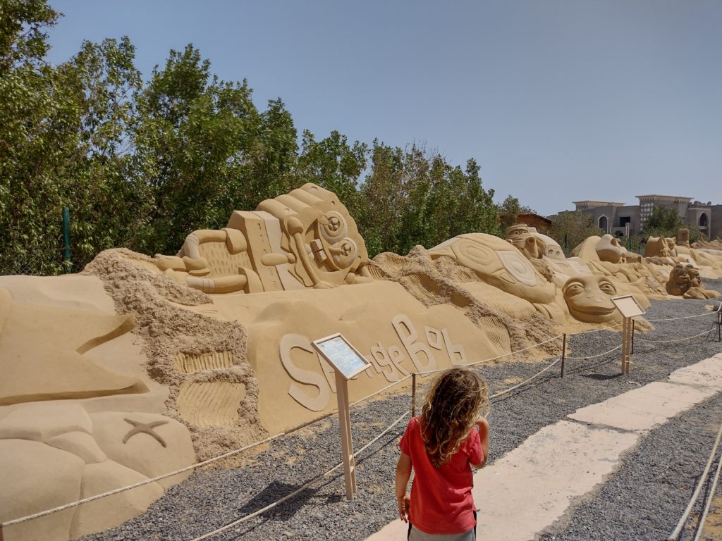 Child walking next to sand sculpture in Sand City Hurghada