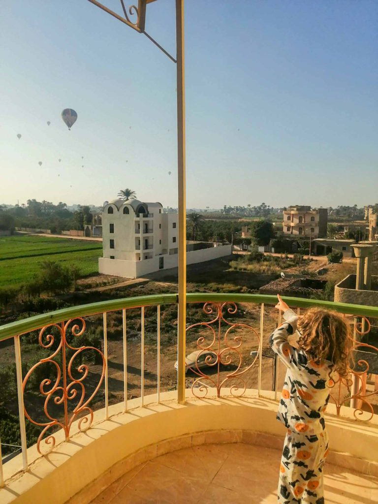 child on balcony looking at hot air balloons in Luxor, Egypt
