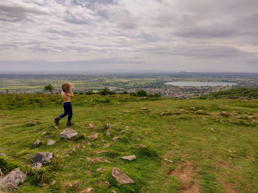 Child walking on Cheddar Gorge with Cheddar Reservoir and Village in Background