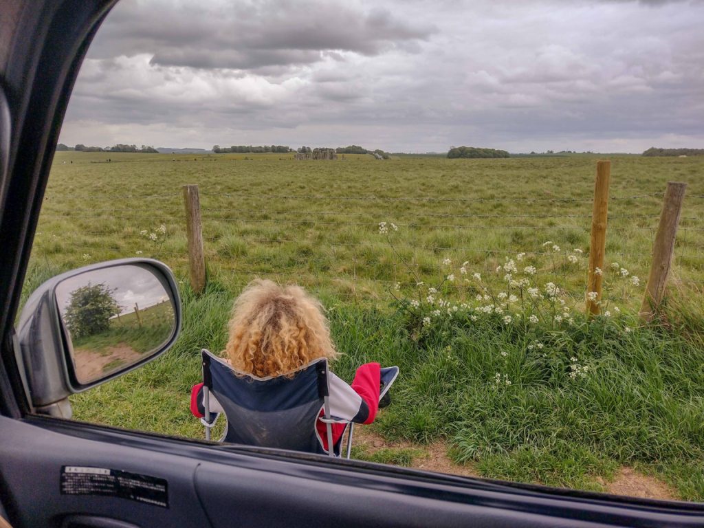 child sat in camping chair next to campervan on The Drove looking at Stonehenge