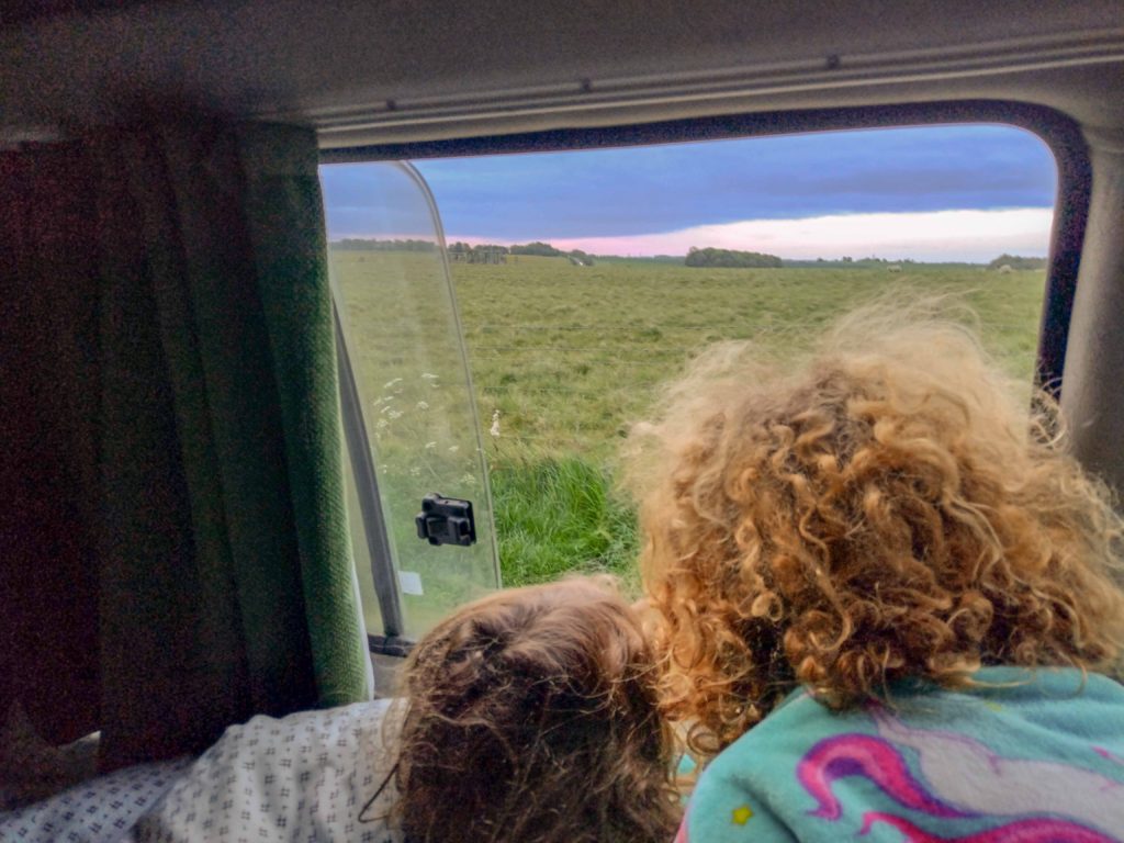 To children in campervan looking through window at Stonehenge during sunrise