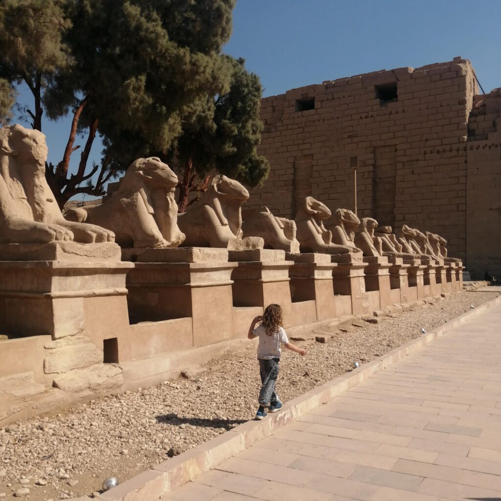 Child walking next to Ram Statues in Karnak Temple in Luxor Egypt
