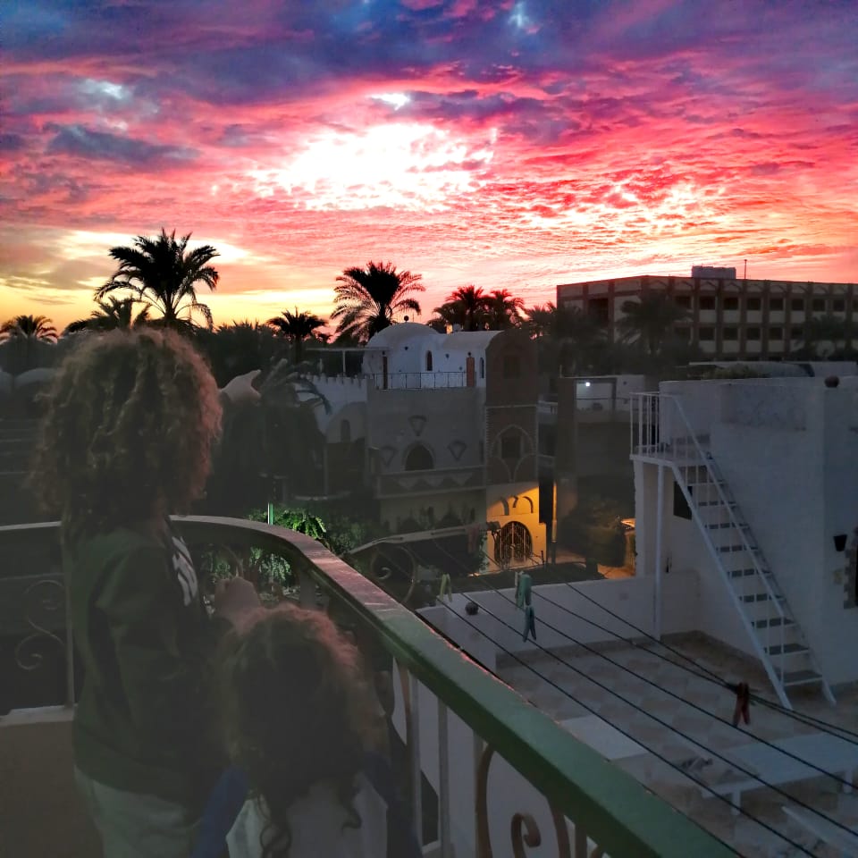 Two children on balcony looking at evening sky in Luxor Egypt