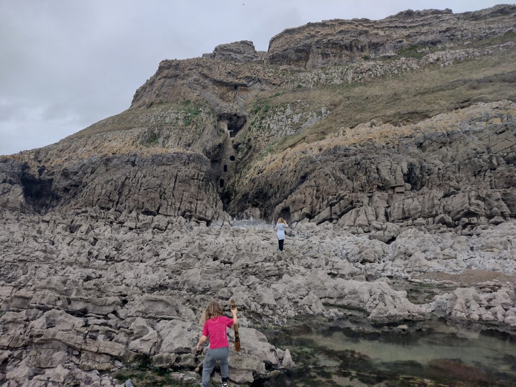 Two Children walking on rocks towards Culver Hole in Wales